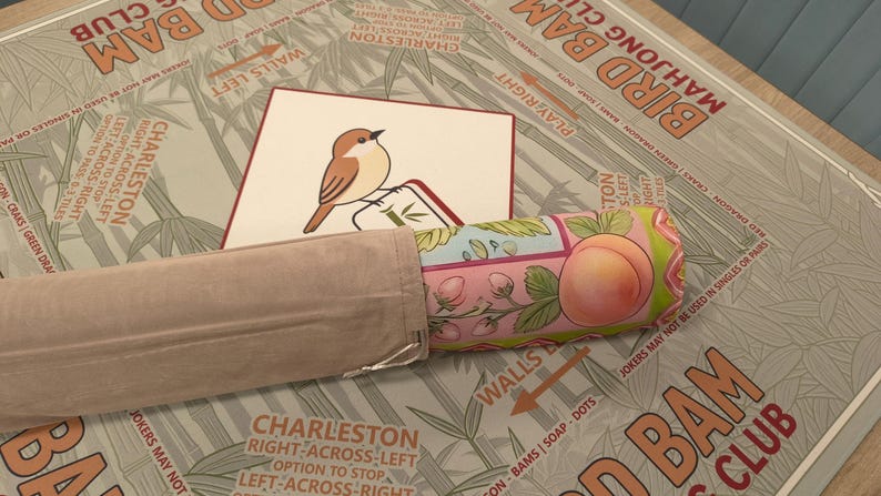 K&ouml;nnte beinhalten: Ein Bird Bam Club Mahjong-Set mit einer Vogelillustration auf einer Karte, einer Pfirsich-Themen-Rolle und einem beigefarbenen Stoffetui. Das Set liegt auf einer Oberfl&auml;che mit Bambusmuster.