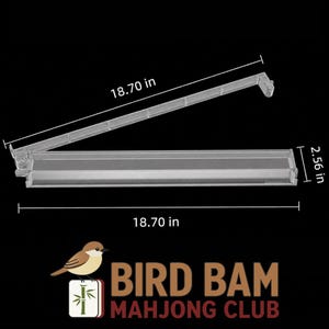 May include: A clear acrylic mahjong tile rack with a hinged design. The rack measures 18.70 inches in length and 2.56 inches in height. The text BIRD BAM MAHJONG CLUB is displayed below the rack alongside a small illustration of a bird.
