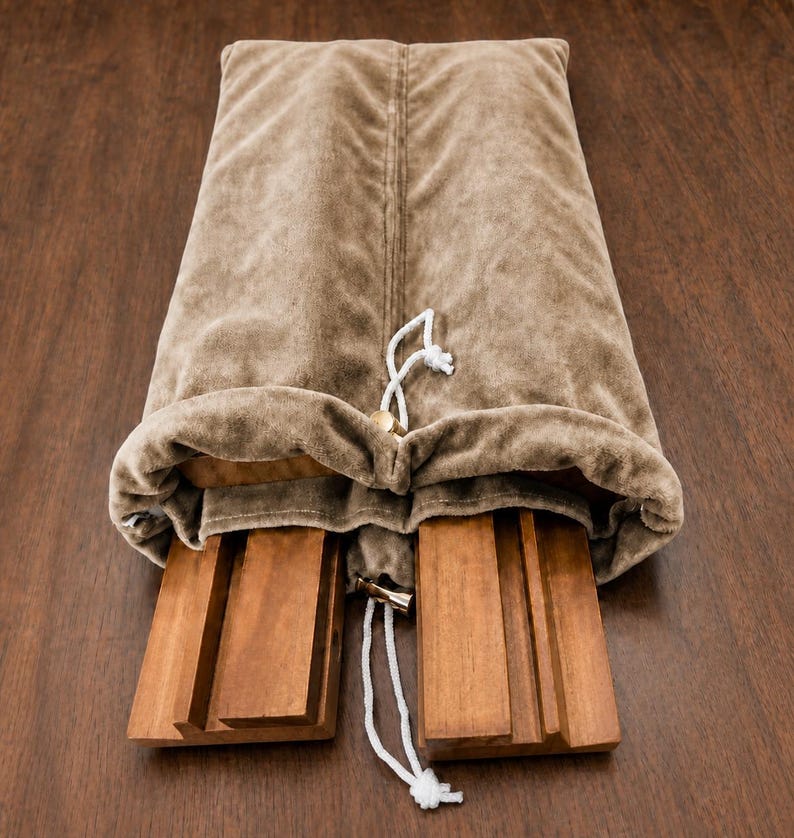 May include: A rectangular, light brown velvet storage bag with a drawstring closure, partially open to reveal two separate, smooth, medium-toned wooden boards with grooved channels running vertically along their surfaces.