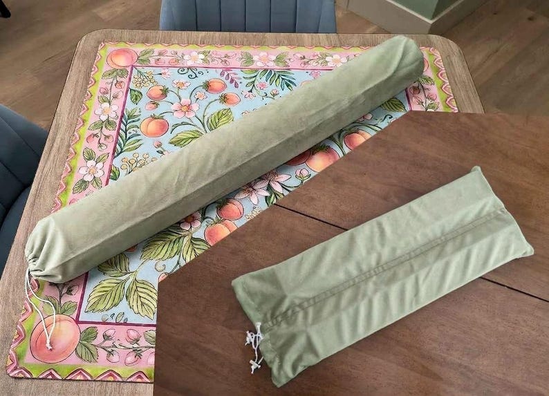 May include: Two sage green fabric storage sleeves with white drawstring closures. One sleeve is long and cylindrical, while the other is shorter and rectangular. Both items feature a soft, matte texture and are designed for organizing or protecting items.