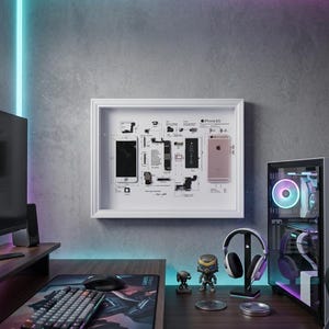 May include: A framed diagram of an iPhone 6S, with a disassembled phone and components. A pink iPhone 6S is displayed next to the diagram. A gaming setup includes a keyboard, mouse, and computer with a glowing case.