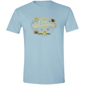 May include: Light blue t-shirt with a graphic design that includes the text "Making Core Memories". The design features gold rings, a camera, a castle, and a heart-shaped balloon.