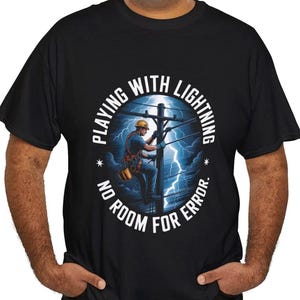 May include: Black t-shirt with a graphic of an electrician working on a power line during a lightning storm. The text reads "PLAYING WITH LIGHTNING, NO ROOM FOR ERROR."