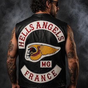 Puede incluir: Un chaleco de cuero negro con un gran parche bordado en la espalda. El parche muestra el texto HELLS ANGELS en rojo sobre una banda blanca curva, un emblema central de calavera alada en amarillo y rojo, las letras MG y FRANCE en rojo.