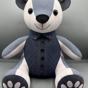 Puede incluir: Un oso de peluche hecho a mano con un patrón de cuadros azul marino y blanco en las orejas, patas y partes del cuerpo. El oso lleva un chaleco azul marino con botones negros y una tela a rayas blancas y rosas.