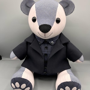 May include: A plush teddy bear wearing a black suit jacket and a patterned shirt. The bear's head and ears are made of a black and white checkered fabric. The bear's paws have white paw prints. The text "Memories Made by Me" is at the bottom.