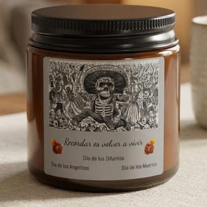 Peut inclure: Un pot à bougie en verre brun avec un couvercle noir et une étiquette rectangulaire présentant une illustration en noir et blanc d'un squelette portant un sombrero. L'étiquette porte le texte : Recordar es volver a vivir, Dia de los Difuntos, Dia de los Angelitos, Dia de los Muertos.