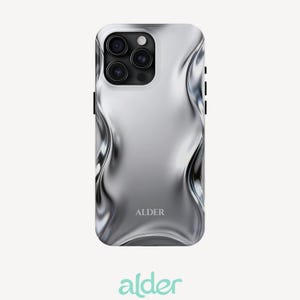 May include: A smartphone case with a metallic silver finish and a liquid-like, wavy, distorted surface texture. The case features a triple-lens camera cutout at the top left and the word ALDER printed in a serif font near the bottom center.