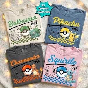 May include: Four t-shirts featuring Pokemon characters. The cream shirt shows Bulbasaur, the blue shirt shows Pikachu, the gray shirt shows Charmander, and the pink shirt shows Squirtle. Each includes the character name, 1996, and a Pokeball.