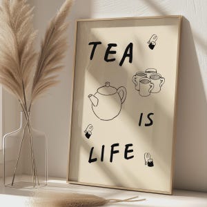 Peut inclure: Une affiche murale encadrée rectangulaire sur fond beige avec des dessins au trait noirs représentant une théière, trois tasses et trois sachets de thé. Le texte TEA IS LIFE est imprimé en caractères noirs gras et manuscrits au centre.