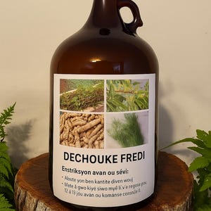 May include: A large brown glass jug with a black cap and handle, featuring a white label with text and images of plants. The label reads "DECHOUKE FREDI" and includes instructions. The jug is displayed on a wooden stump.