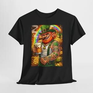 Puede incluir: Camiseta negra con una colorida ilustración de un duende tatuado con sombrero verde y cigarro, sosteniendo una jarra de cerveza. Un arcoíris y monedas de oro están en el fondo. El duende lleva una camiseta sin mangas blanca y un peto verde.
