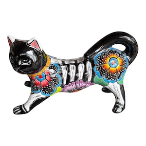 May include: A black ceramic cat figurine featuring a glossy finish, decorated with vibrant hand-painted floral patterns in red, orange, yellow, blue, and purple, along with white skeletal rib details across the torso and a curved tail.
