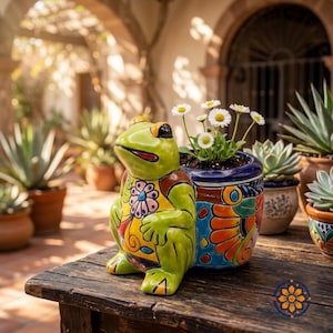 May include: A whimsical ceramic frog planter with a vibrant green body, yellow vest, and a blue and orange flower pot. The frog is sitting on a weathered wooden table, with daisies in the pot. Other potted plants are in the background.