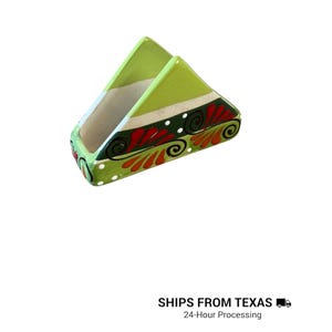 Peut inclure: Un porte-serviettes triangulaire en c&eacute;ramique avec une section sup&eacute;rieure vert citron vif et une base vert fonc&eacute;. La base est orn&eacute;e de motifs floraux peints &agrave; la main en rouge et orange, de spirales noires et de petits points blancs sur le bord.