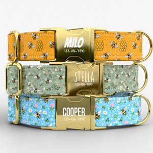 May include: Three personalized dog collars with gold-colored hardware. The top collar is yellow with a bee and honeycomb pattern, the middle is green with bees and flowers, and the bottom is blue with bees and flowers. Each collar has a name and phone number.