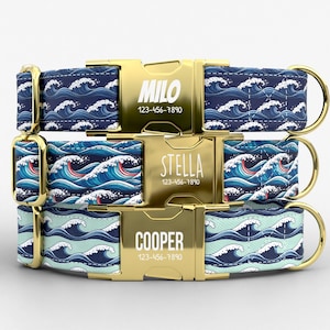 May include: Three personalized dog collars with gold-colored buckles. Each collar features a wave pattern in shades of blue and white. The buckles are engraved with a name and phone number: Milo, Stella, and Cooper.