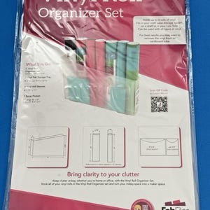 May include: A Totally-Tiffany Vinyl Roll Organizer Set in clear plastic packaging. The set includes a storage tray, six vinyl roll sleeves, and two scrap pockets. The packaging features diagrams with dimensions in inches and a QR code for information.