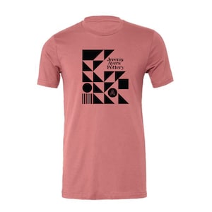 May include: A pink t-shirt with a black geometric design and the text "Jeremy Ayers Pottery" on the front.