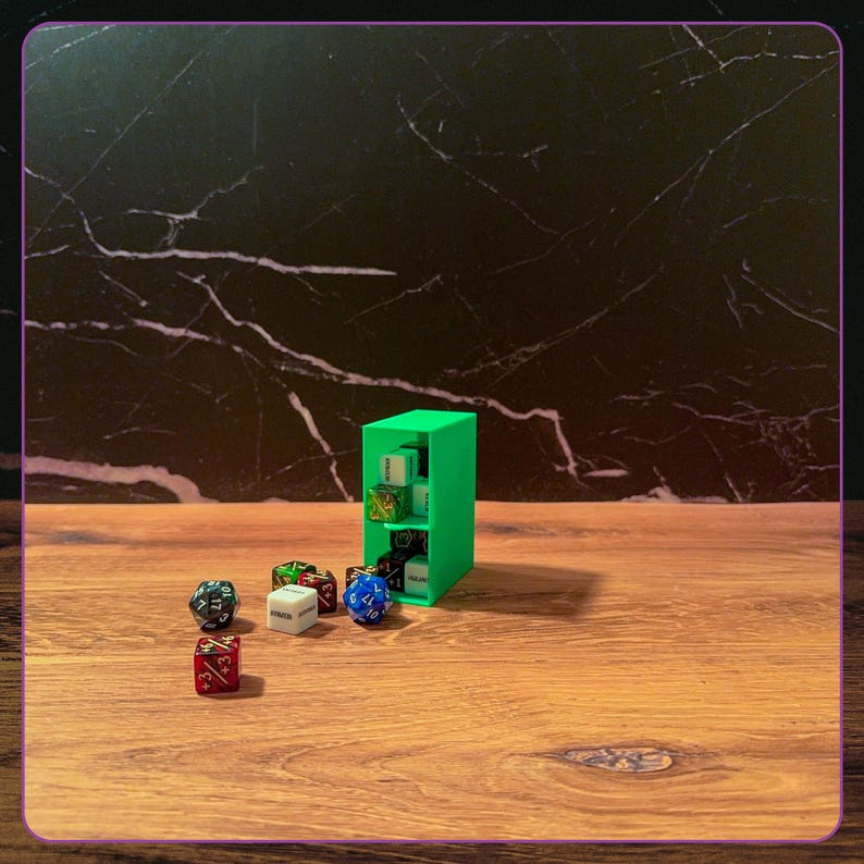 May include: A bright green rectangular storage tower with two internal shelves holding several multi-sided dice. Scattered in front of the tower are various polyhedral dice in colors including red, white, blue, and black with printed numbers.