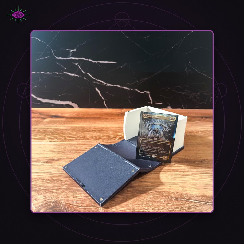 May include: A dark blue and white plastic deck box with a hinged lid, featuring a rectangular trading card titled Kibo, Uktabi Prince displayed upright in the center. The box has a textured finish and visible circular fasteners on the exterior.