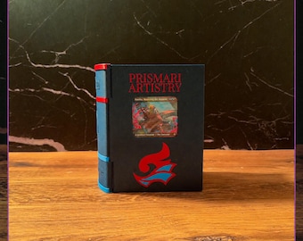May include: A black deck box with the text PRISMARI ARTISTRY in red, featuring a central card display window showing a creature card, and a red and blue flame-like emblem below. The side of the box is blue with red accents.