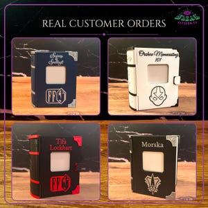 May include: Four rectangular book-shaped boxes with central square cutouts. The top left is blue with silver accents and text. The top right is white with black text and a character icon. The bottom left is black with red accents and text. The bottom right is black with silver accents and text.