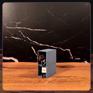 May include: A grey, rectangular, two-tiered storage organizer made of plastic. The top shelf contains several multi-sided gaming dice in red and black. The bottom shelf holds a white rectangular token with the word HASTE printed in black.
