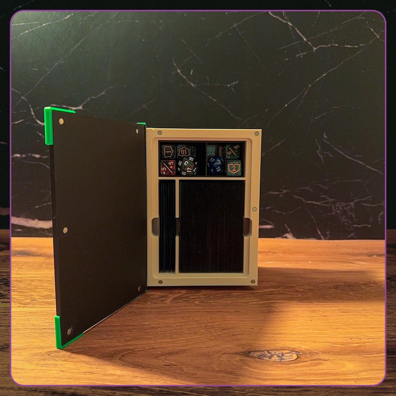 May include: A rectangular storage box with a hinged black door featuring bright green corner accents. The interior is off-white and contains a top compartment filled with various multi-sided gaming dice and a larger lower section holding a deck of cards.