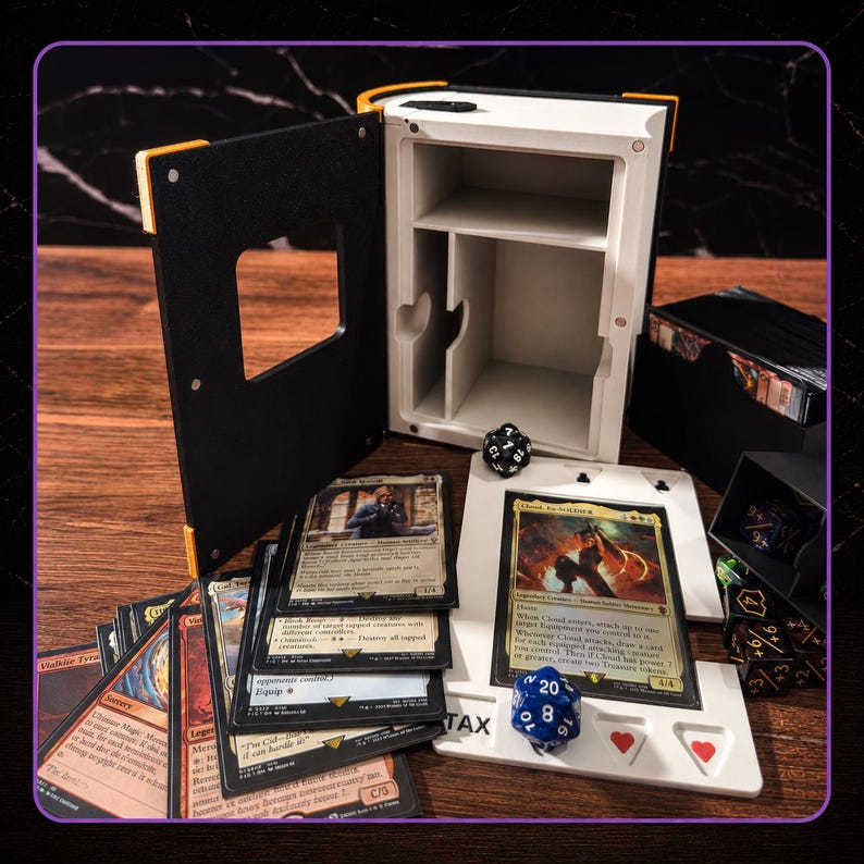 May include: A white and black book-shaped storage box with an open cover, containing a white card display stand with two red heart icons. The set includes multiple trading cards, a black twenty-sided die, and a blue twenty-sided die.