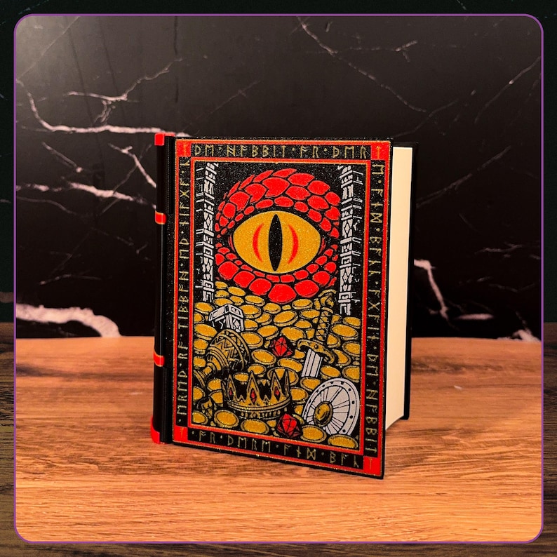 May include: A black book with a red spine and a front cover illustration featuring a large red dragon eye surrounded by gold coins, a crown, a sword, and a shield. The border contains the text DM NFBBIT FR DMR and other runic characters.