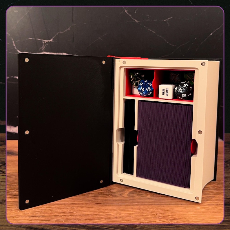 May include: A black and white book-shaped storage box with a hinged cover. The interior features a red-lined compartment containing several multi-sided gaming dice, a white cube with the text FIRST STRIKE, and a stack of dark purple playing cards.