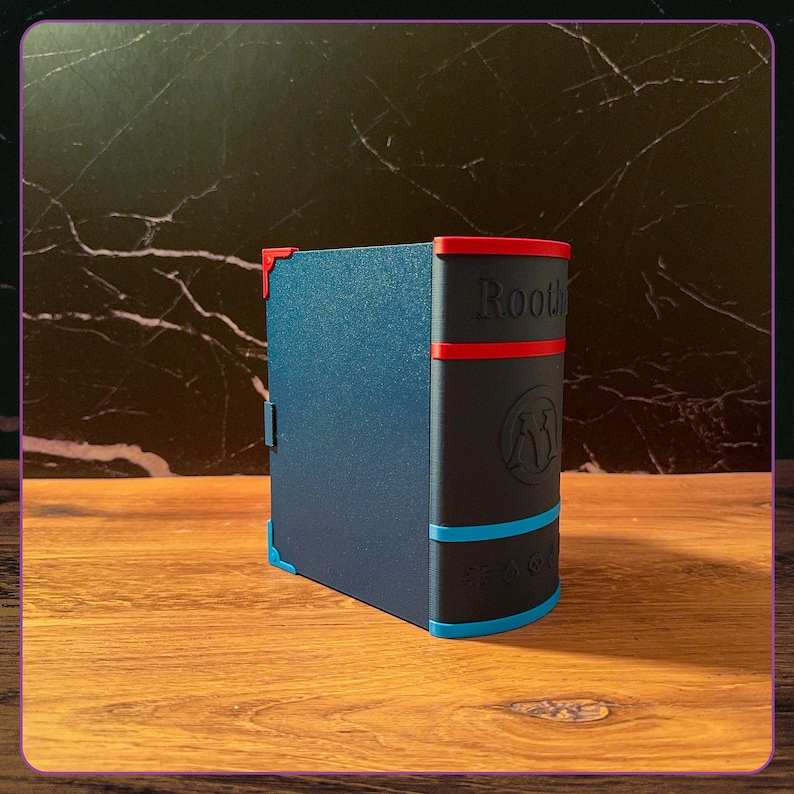 K&ouml;nnte beinhalten: Eine dunkelblaue, buchf&ouml;rmige Aufbewahrungsbox mit schwarzem Buchr&uuml;cken. Der R&uuml;cken ist mit roten und blauen horizontalen Streifen, dem Schriftzug "Rooth", einem kreisf&ouml;rmigen Logo und f&uuml;nf kleinen gepr&auml;gten Symbolen versehen.