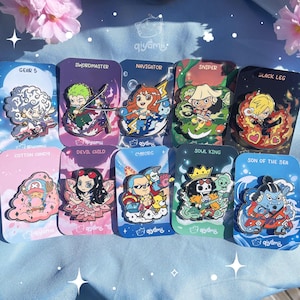 May include: A selection of enamel pins with anime character designs, each on a card with a character's name. The pins display vivid colours and intricate details. Characters include "Swordmaster" and "Black Leg". Ideal for collectors of anime merchandise.