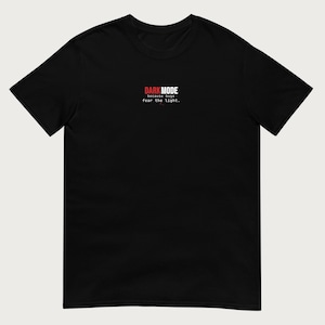 May include: A black short-sleeved t-shirt featuring the text "DARK MODE because bugs fear the light." printed in red and white on the center chest. The shirt has a crew neckline and a standard fit, showcasing a clean and simple design.