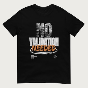 May include: A black short-sleeve t-shirt featuring the white distressed text NO VALIDATION, with the word NEEDED in orange below it, underlined by a white oval. Smaller text reads I KNOW. I'M DOING THIS FOR ME, next to a small white target icon.
