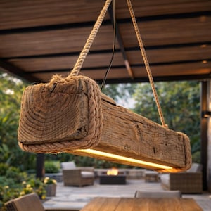 Puede incluir: Luminaria rectangular de madera rústica, suspendida por gruesas cuerdas. La madera envejecida tiene vetas visibles y está envuelta con cuerda en cada extremo. Una fuente de luz lineal y cálida ilumina la parte inferior. Ideal para espacios exteriores o interiores.