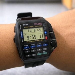 以下が含まれることがあります： 電卓とリモコン機能を備えた黒いカシオデジタル時計。 時計には時刻と日付が表示され、入力用のキーパッドが付いています。 時計は黒いストラップが付いています。