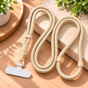 Puede incluir: Un cordón de cuerda beige con un diseño cilíndrico liso, que presenta detalles en imitación de cuero beige a juego y un cierre giratorio de metal plateado unido a una pieza de conexión blanca, rectangular y plana para asegurar objetos.