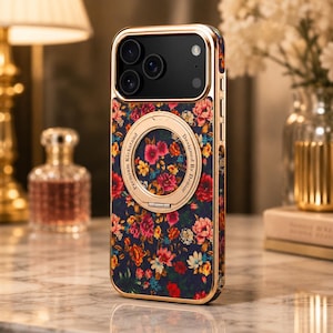 May include: A smartphone case with a dark blue background featuring a colorful floral pattern of red, pink, and yellow flowers. The case has a gold-toned metallic frame and a circular gold-toned kickstand with the text Premium Kickstand Designed By Denior.
