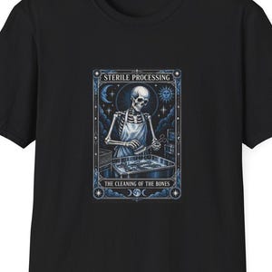Könnte beinhalten: Ein schwarzes T-Shirt mit einem Grafikdruck eines Skeletts in einer Schürze, das chirurgische Instrumente in einer Schale reinigt. Der Text lautet STERILE PROCESSING und THE CLEANING OF THE BONES, umrahmt von himmlischen Motiven wie Mond und Sonne.