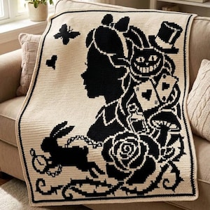 May include: A rectangular crochet blanket featuring a black and cream color scheme. The design displays a silhouette of a girl in profile, a grinning cat, a rabbit with a pocket watch, playing cards, a rose, a butterfly, and a top hat.