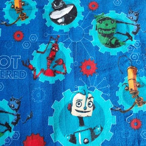 Peut inclure: Tissu bleu avec un motif répété de robots de dessins animés de différentes couleurs, dont le rouge, le vert et le jaune. Les robots sont placés dans des engrenages bleus et des roues dentées rouges. Les mots "ROBOT POWERED" sont imprimés sur le tissu.