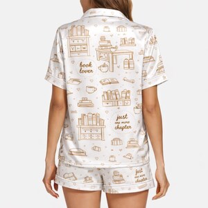 May include: White pajama set with a repeating pattern of books, bookshelves, and coffee cups in a brown color. The words "book lover" and "just one more chapter" are also printed on the set.