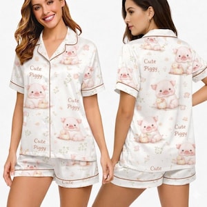 May include: White pajama set with a repeating pattern of cute pink pig illustrations and the text "Cute Piggy." The set includes a short-sleeved button-up top and matching shorts, both trimmed with brown piping.
