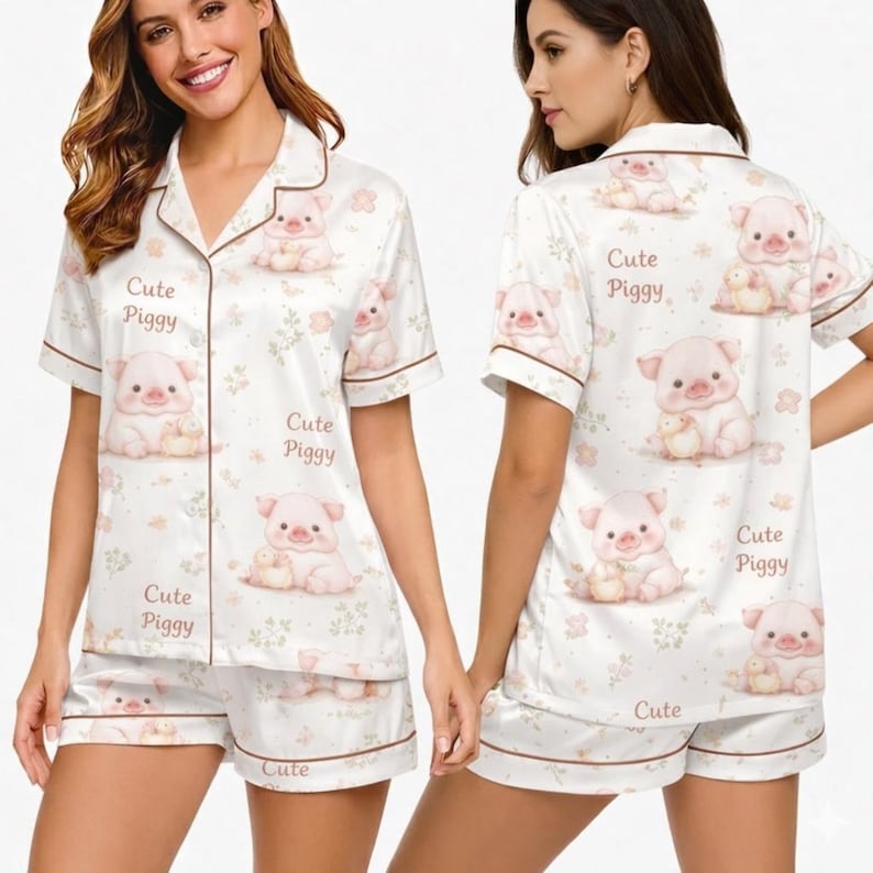 May include: White pajama set with a repeating pattern of cute pink pig illustrations and the text "Cute Piggy." The set includes a short-sleeved button-up top and matching shorts, both trimmed with brown piping.