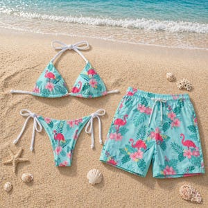 May include: A turquoise bikini and matching swim trunks set with a flamingo and floral print. The bikini top is a triangle style with white ties, and the bottoms are a classic cut. The swim trunks have a drawstring waist.