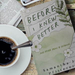May include: A book titled "Before I Knew Better" with floral accents and the author's name, alongside a cup of coffee, sugar cubes, and a newspaper on a rustic wooden surface. The book cover is light green and white.