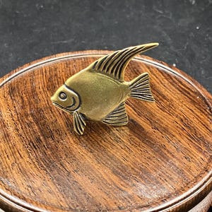 May include: A white ceramic mug with a black handle and the text "But First, Coffee" in a black, handwritten-style font. The mug is on a white surface.