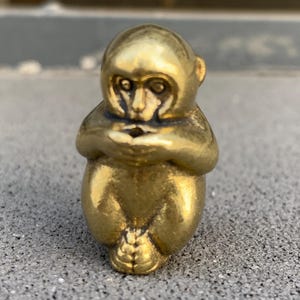 May include: A white ceramic mug with a black handle and the text "But First, Coffee" in a black, handwritten-style font. The mug is on a white surface.